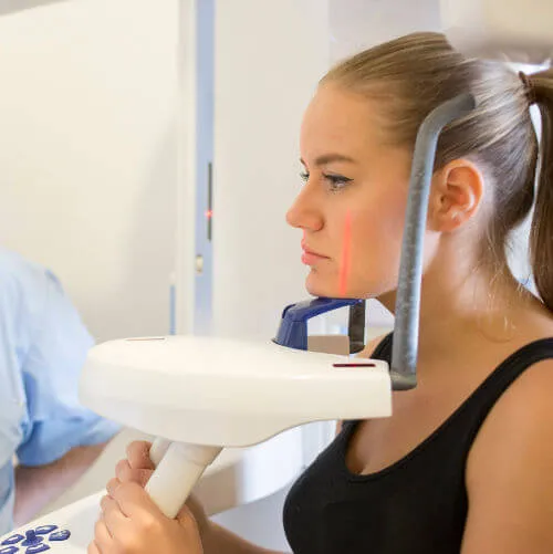Patientin an einem zahnmedizinischen Röntgengerät